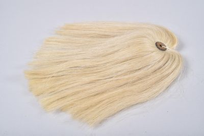 un gros plan sur une mèche de cheveux blonds posée sur une surface blanche