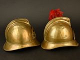 pair of brass helmets with a red pom pom on top