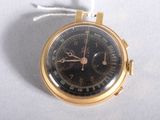 a gold watch with a black face on a white surface