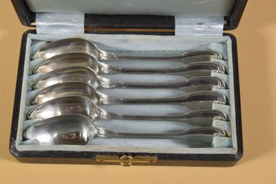 six cuillères dans un étui posé sur une table