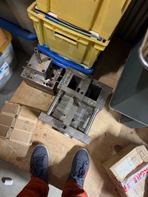 une personne debout sur un plancher en bois, à côté d'une boîte jaune