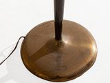 underside view of a brass plated floor lamp with a black metal base
