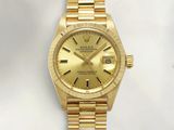 an image of a gold rolex watch sitting on a white surface