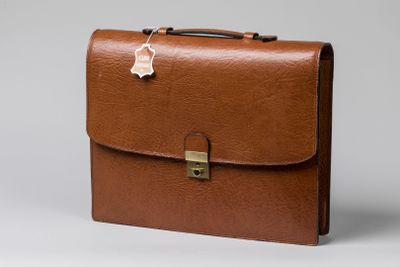 porte-documents en cuir marron avec un fermoir métallique sur fond gris
