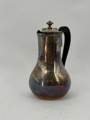 a silver coffee pot with a black handle on a white table