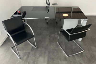 a desk with two chairs and a computer on it