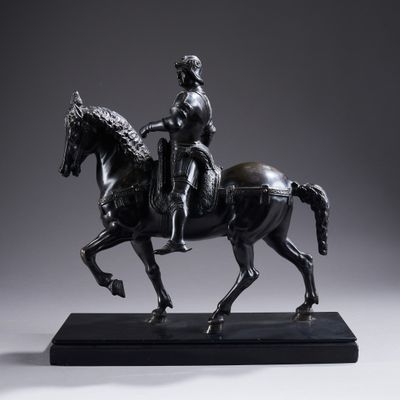an antique bronze statue of a man riding a horse on a marble base