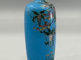 a blue vase with a bird and flowers on it