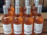 Six bouteilles de vin rosé sont alignées sur une table en bois