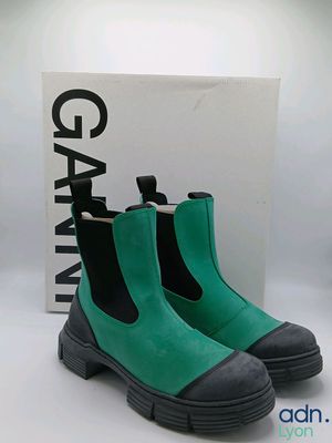 Les bottes vertes et noires se trouvent à côté d'une boîte blanche