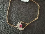 a gold bracelet with a flower charm on it