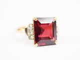 gros plan d'une bague avec une pierre rouge entourée de diamants