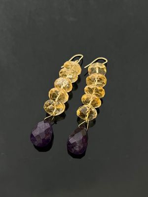 a pair of amethorate and citrine earrings on a black surface