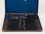 six knives in a case on a white surface