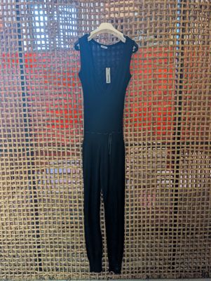 a black jumpsuit on a hanger in front of a wall