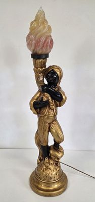 figurine dorée et noire représentant un homme tenant une torche