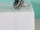 an image of a blue diamond ring sitting on top of a white marble block
