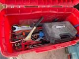 une boîte rouge contenant des outils, posée par terre