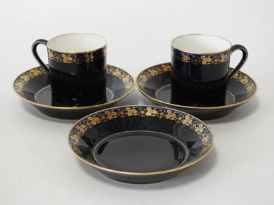 three black and gold coffee cups and saucers on a white surface