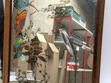 a mirror with a picture of a bird on it and a vase with a plant in it