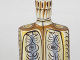 a small bottle with a design on it on a white surface