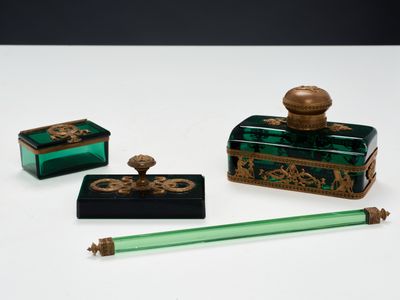 trois morceaux de verre vert ornés de motifs dorés et un stylo vert