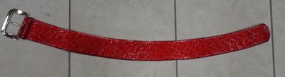 une ceinture rouge avec une boucle argentée sur un parquet