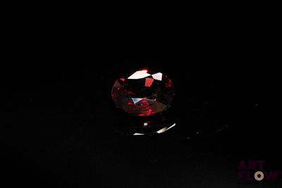 une image montrant un gros plan d'un diamant rouge sur une surface noire