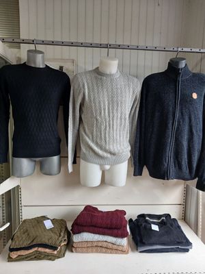 several sweaters and jackets are on display in a clothing store