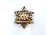 an image of a gold broochle with a flower design on it