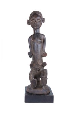 statue représentant un homme tenant un bébé dans ses bras, posée sur un socle en bois
