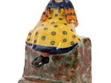 a close up of a figurine of a woman sitting on a rock