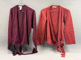 deux vestes rouges et roses accrochées à un mur blanc