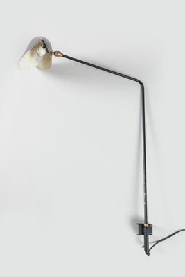 une lampe noire et blanche accrochée au mur, à côté d'un mur blanc
