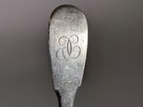 a spoon with a monogram on it sitting on a table