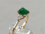 a close up of a gold ring with a green emerald stone