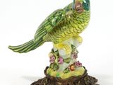 une figurine représentant un perroquet vert posé sur une souche d'arbre