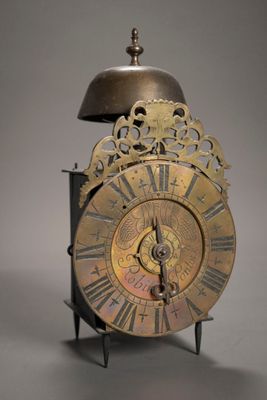une horloge posée sur un socle, surmontée d'une cloche