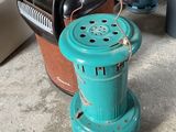 a green stove sitting in a garage next to a chair
