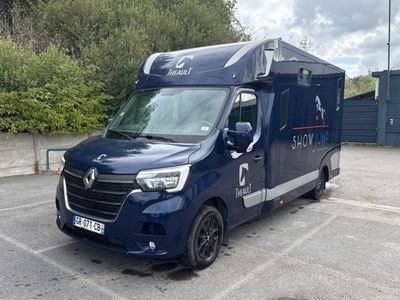 une camionnette bleue garée sur un parking, avec des arbres en arrière-plan