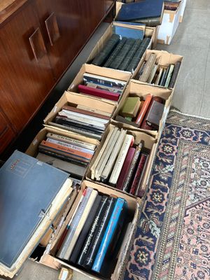 boxes of books are lined up on the floor next to a dresser