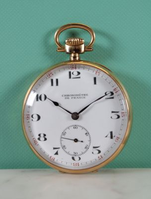 a gold pocket watch sitting on a table with a green wall in the background