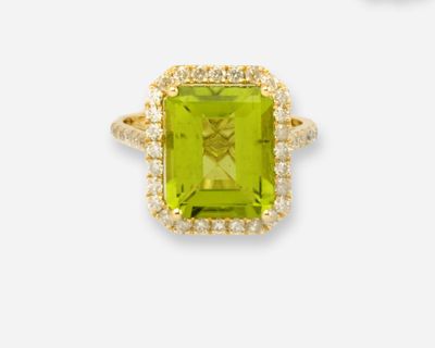 gros plan d'une bague avec une pierre verte entourée de diamants