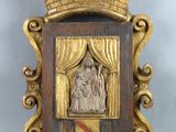une image représentant une plaque en bois sur laquelle figure la statue d'une femme sur une scène