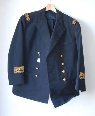 veste bleu marine avec des boutons dorés et des bordures dorées, suspendue à un cintre