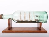a glass bottle with a ship in it on a wooden stand