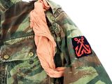 camouflage jacket with orange and black patches on the chest and sleeves