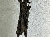 statue d'un homme tenant une faux, posée sur une surface blanche
