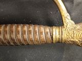 a close up of a sword with a gold handle on a black surface