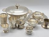 a silver tea set with cups and saucers on the table